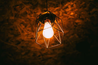 Illuminated light bulb hanging in the dark