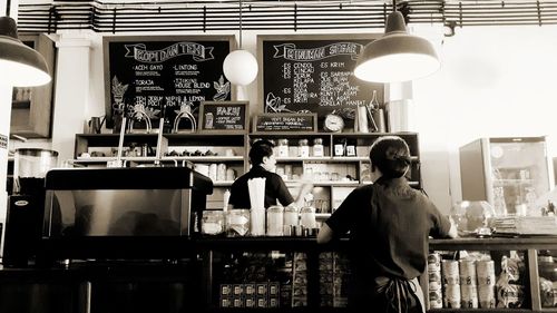 Woman standing in front of illuminated restaurant