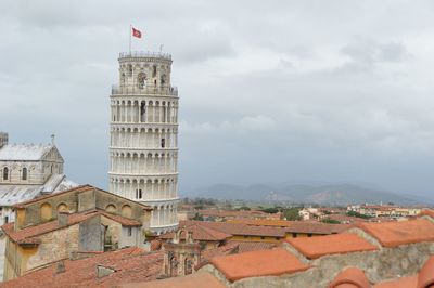 Leaning tower of pisa in city against cloudy sky