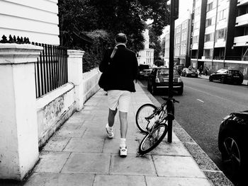 Rear view of man riding bicycle on city