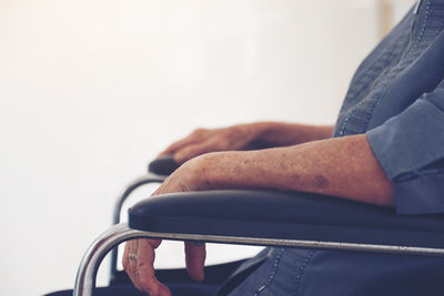 Side view of senior woman sitting on wheelchair by window