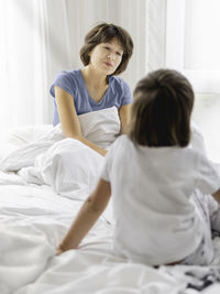 Kid wakes his mother up. sleepy disheveled mom sits in bed. uneasy life as parent. 