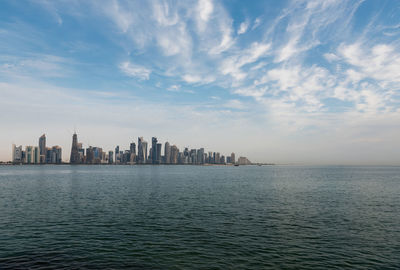 Scenic view of sea by buildings against sky