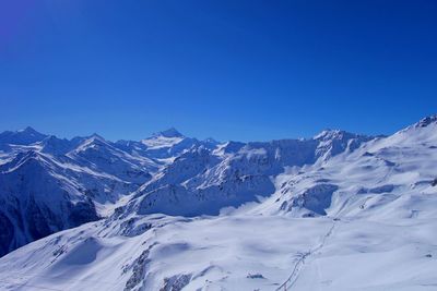Scenic view of snowcapped mountains against clear blue sky