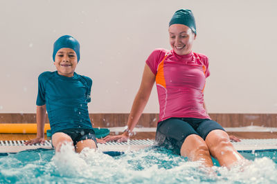 Boy learning to swim in pool with teacher