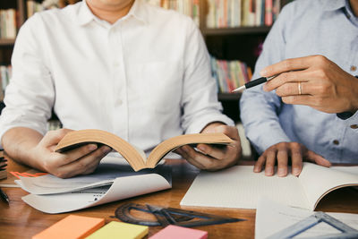 Midsection of man working with book on table