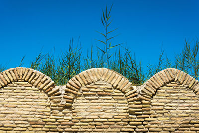 Low angle view of stone wall against blue sky