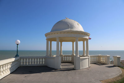 Gazebo by sea against clear blue sky