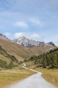 Road by snowcapped mountains against sky