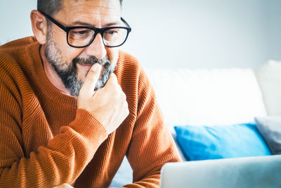 Portrait of young man using mobile phone while sitting on sofa at home