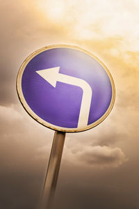 Low angle view of arrow sign against sky during sunset