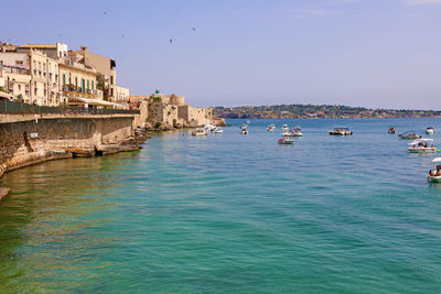 Sailboats in sea against clear blue sky