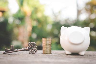 Close-up of coins stack amidst antique key and piggy bank on wooden table