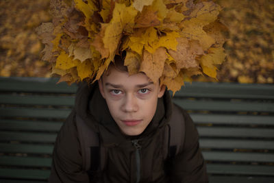 Portrait of teenage boy with yellow leaves in park during autumn