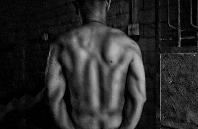 Rear view of shirtless man standing at home