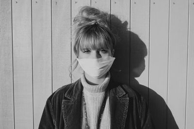 Portrait of woman wearing mask standing against wall