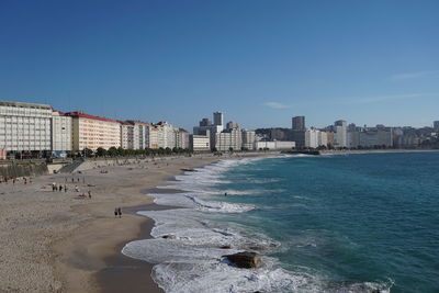 Sea by buildings against clear blue sky