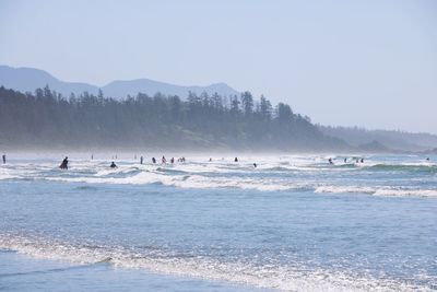 People at beach against clear sky