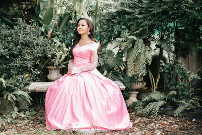 Full length of woman sitting against plants outdoors