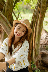 Portrait of smiling young woman by tree