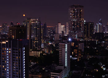 Illuminated buildings in city against sky at night