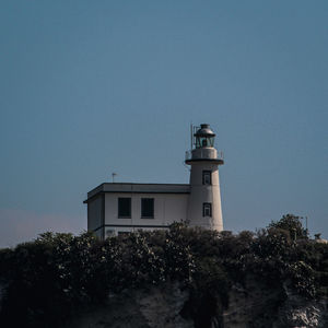 Low angle view of lighthouse by building against sky