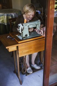 Senior woman using an sewing old machine at home