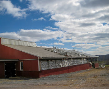 Barn on field by buildings against sky