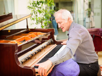 Side view of man playing piano
