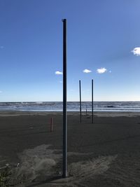 Poles at beach against sky