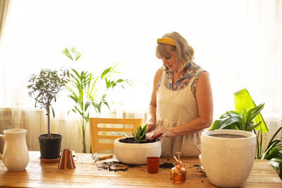 Senior woman potting plant at home