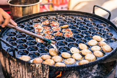 Close-up of person preparing food on barbecue grill