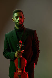 Young man playing violin against black background