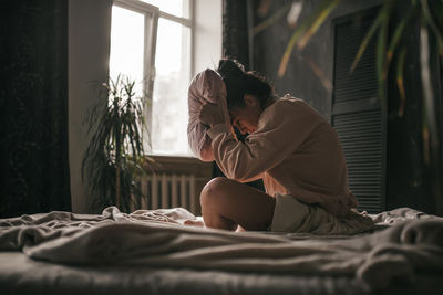 Woman sitting on bed at home