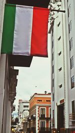 Low angle view of flag against sky in city