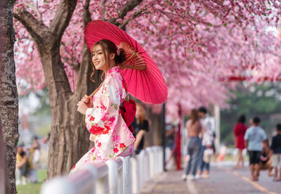 Woman standing on pink cherry blossom tree