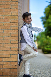 Child poses for fashion leaning on corner, sympathetic and laughing. short-haired dark-haired boy.