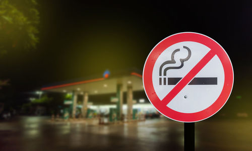 Close-up of no smoking sign against gas station