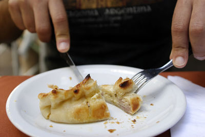 Cutting an argentine empanada stuffed with ham and cheese