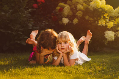 Portrait of girl lying with friend on field at public park