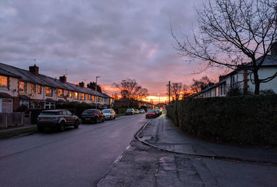 Cars on street in city against sky at sunset