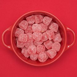 Directly above view of candies in bowl on red background