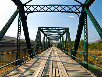 Footbridge over railroad tracks against sky