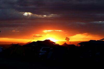 Silhouette car against dramatic sky during sunset