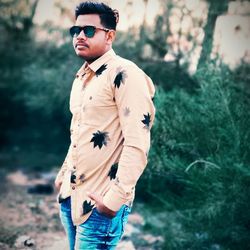 Young man wearing sunglasses standing on land