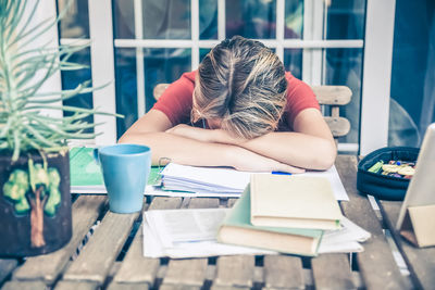 Tired student doing homework at home with school books and newspaper. boy weary due to heavy study