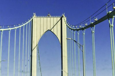 Low angle view of suspension bridge against blue sky