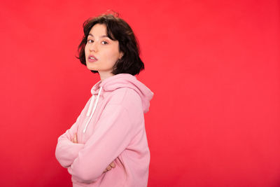 Side view of a smiling young woman against red background