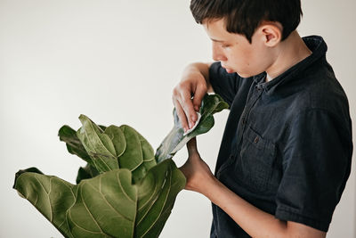 Side view of boy holding plant