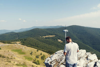 Rear view of man standing on mountain against sky